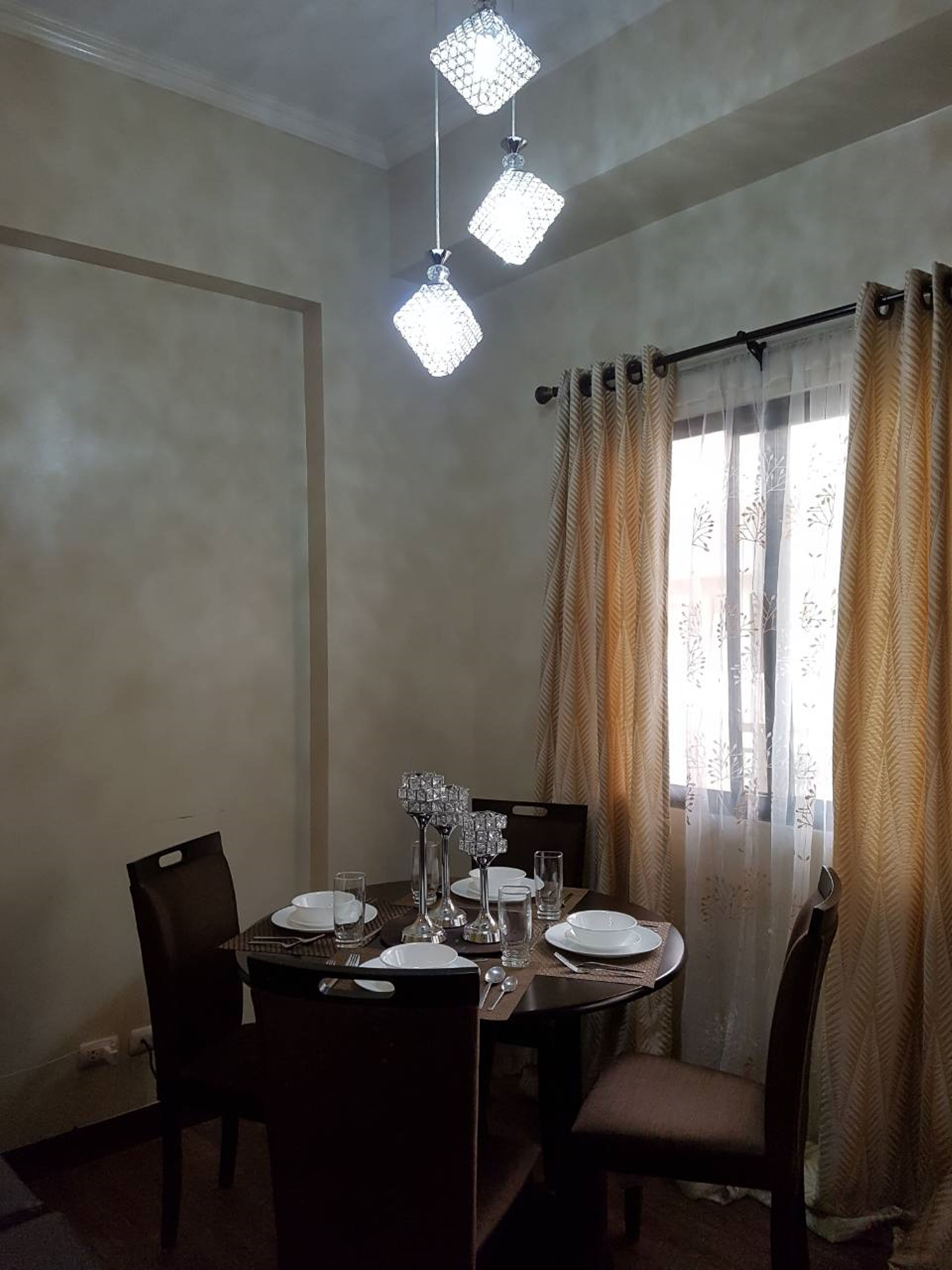 A dining area with a round table set for four, featuring crystal candle holders and clear glassware.