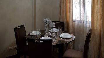 A dining area with a round table set for four, featuring crystal candle holders and clear glassware.
