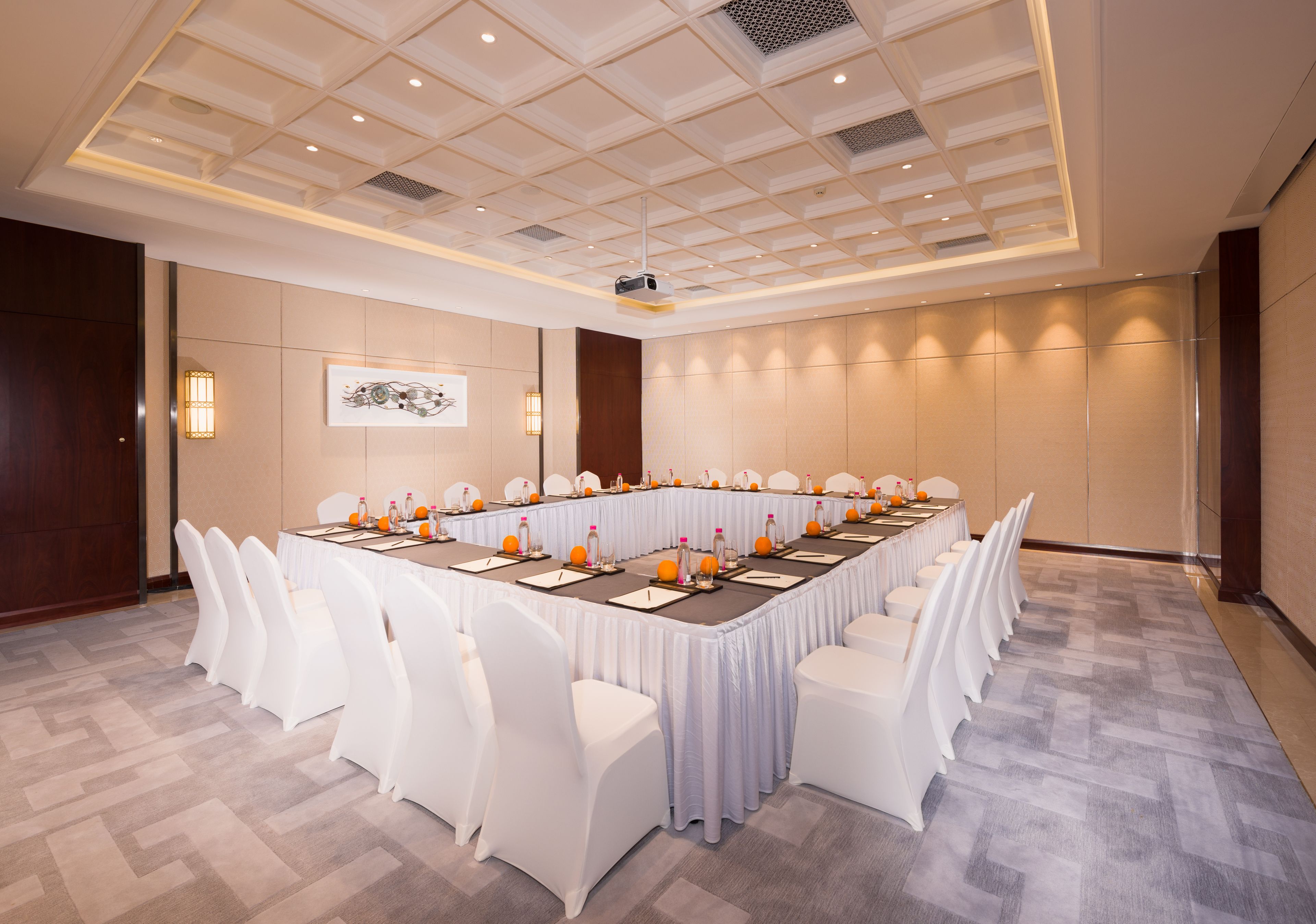 A conference room with a long table, white chairs, and a projector.