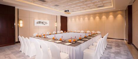 A conference room with a long table, white chairs, and a projector.