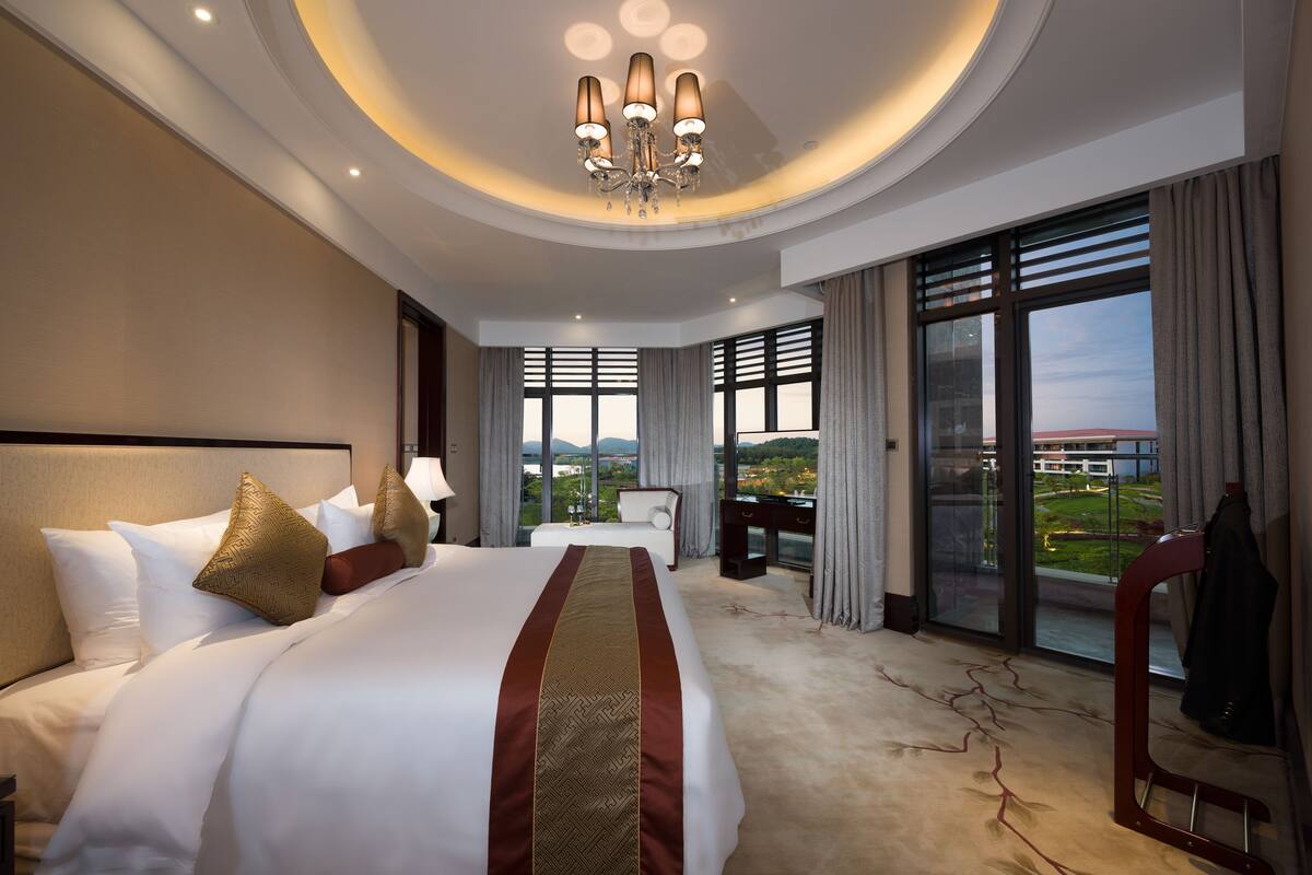 Een hotelkamer met een groot bed, een bureau, een stoel en uitzicht op de omgeving.