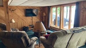 Una habitación acogedora con detalles de madera, un televisor de pantalla plana en la pared, un sofá, una silla y una lámpara.