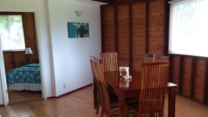Un comedor de madera con una mesa y sillas, techo de madera y una ventana con persianas.