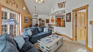 A spacious living room with a large gray sofa, a wooden coffee table, and a ceiling fan. - Direct Unit Access,  Garage, 2 decks, Weber BBQ, Surround Sound Home Theater (Steamboat Springs)