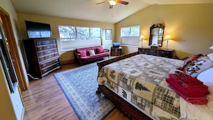 Ein Schlafzimmer mit Bett, Schminktisch, Kommode und Deckenventilator.