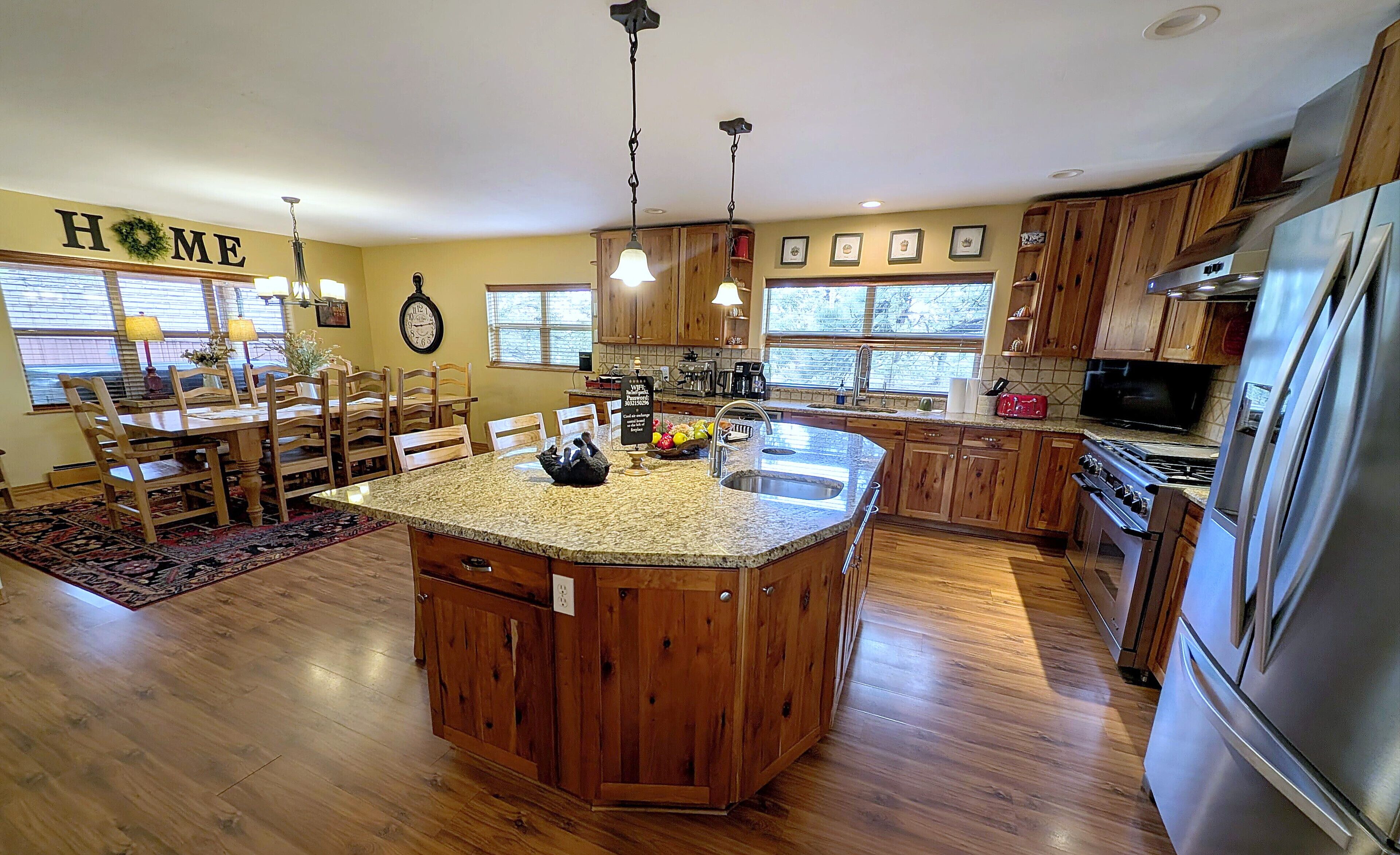 A spacious kitchen with a central island, wooden cabinets, and a stainless steel refrigerator.