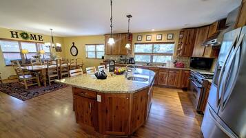 A spacious kitchen with a central island, wooden cabinets, and a stainless steel refrigerator.
