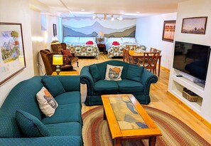 A living room with two sofas, a coffee table, a TV, and a dining area with a table and chairs.