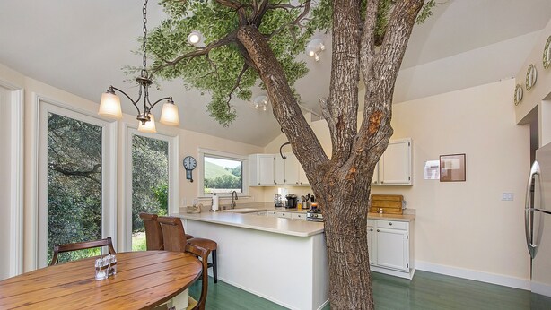 A modern kitchen with a central island, wooden dining table, and chairs. - Riverstone Estate sleeps 12 Pool Bocce Spa (Healdsburg)