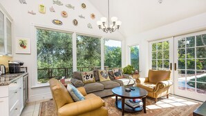 A spacious living room with a large window, a chandelier, and a cozy seating area. - Riverstone Estate sleeps 12 Pool Bocce Spa (Healdsburg)