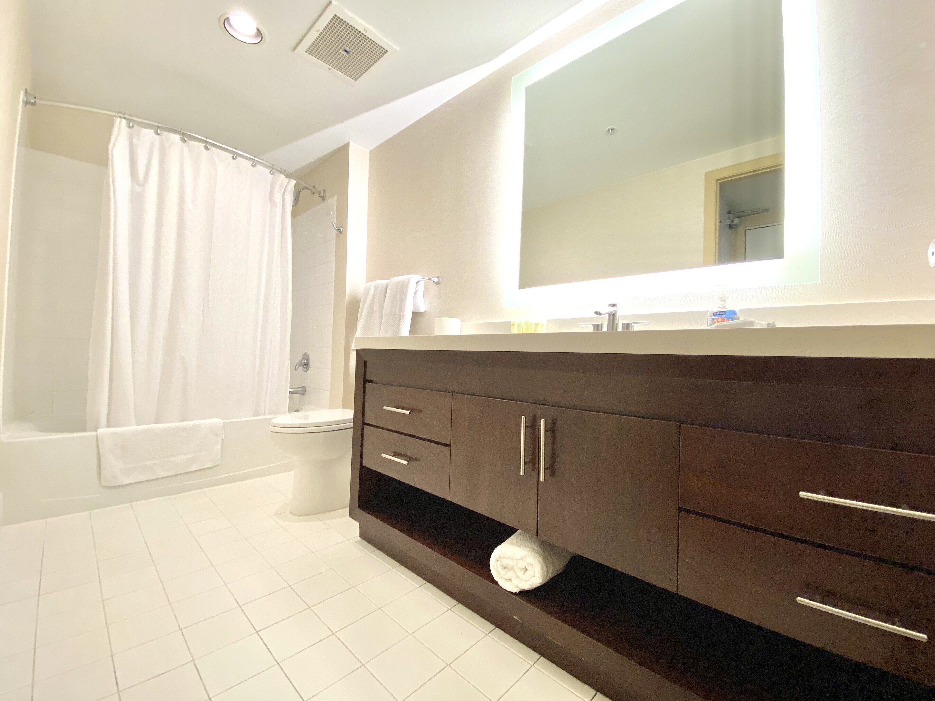 Een moderne badkamer met een bad, toilet en wastafel met spiegel.