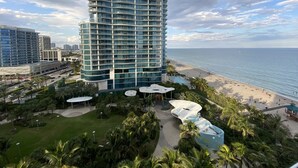 Un hôtel de grande hauteur à la façade incurvée, doté d’un espace piscine et offrant une vue sur la plage.
