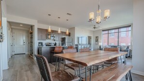Una cocina amplia con una gran mesa de comedor, electrodomésticos modernos e iluminación colgante.