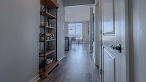 Un pasillo con un armario de madera, un comedor con mesa y sillas, y una cocina al fondo.