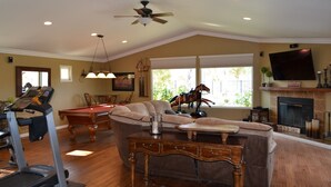 A spacious living room with a pool table, a treadmill, a fireplace, and a television. - Temecula Winery Estate Villa at Longshadow Ranch Winery             Permit #0204 (Temecula)