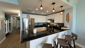 A modern kitchen with a central island, stainless steel appliances, and pendant lighting.