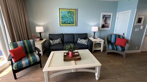 A living room with a sofa, two armchairs, a coffee table, and a painting on the wall.
