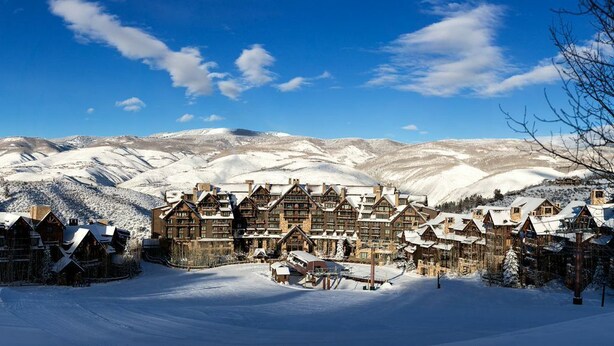 A snow-covered lodge with multiple wooden buildings, a central building with a large roof, and a mountainous backdrop. - RITZ-CARLTON BACHELOR GULCH RESIDENTIAL SUITE located in the Award winning Hotel (Avon)