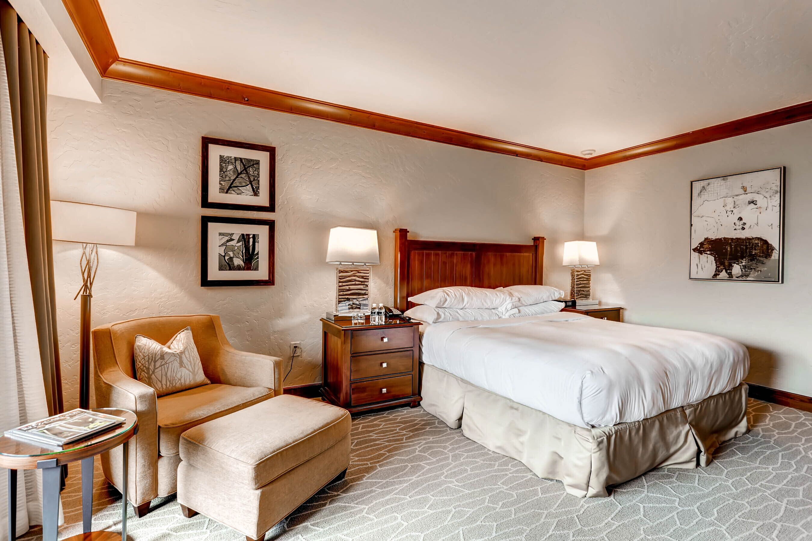 A hotel room with a bed, a chair, a nightstand, and a lamp.
