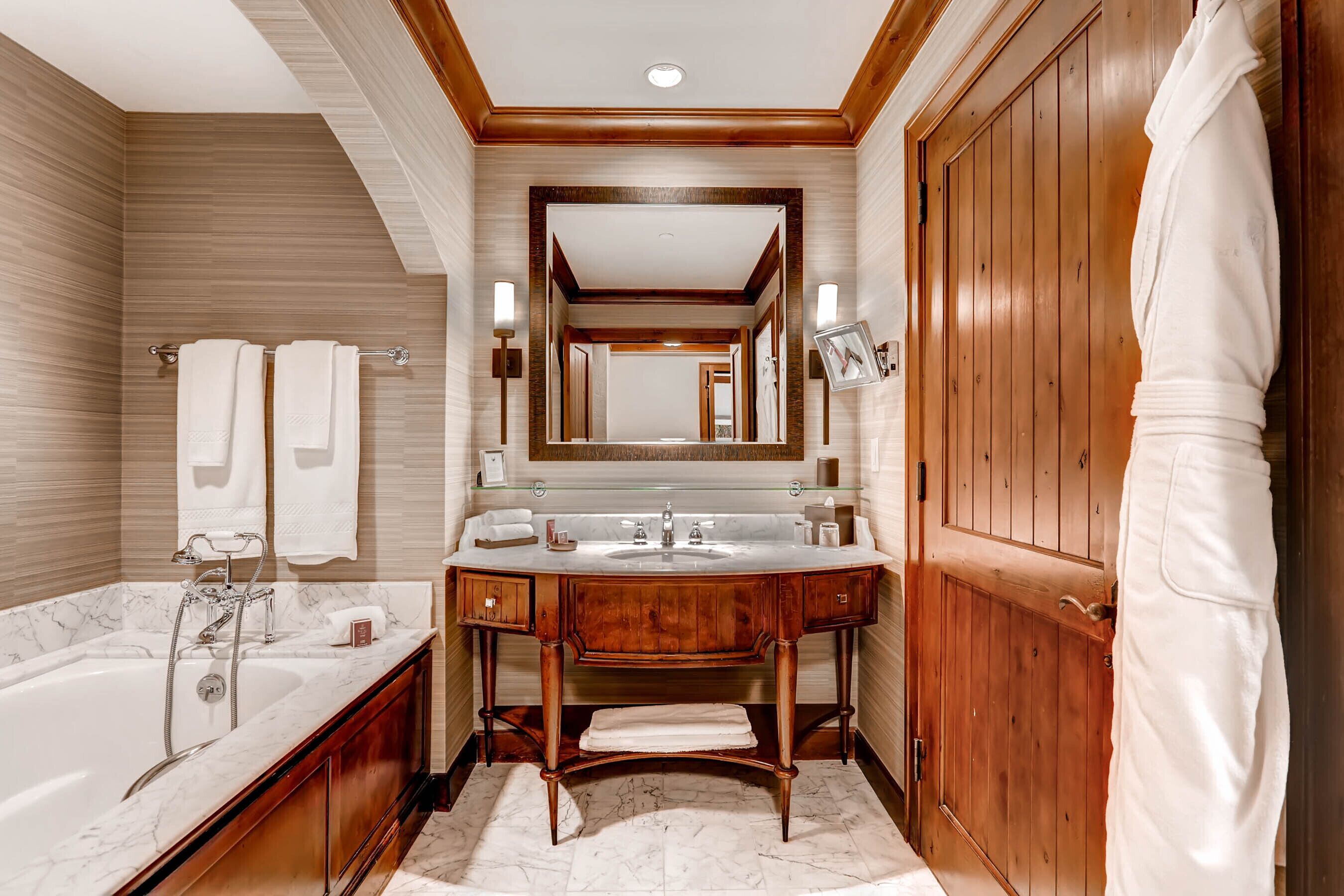 A modern bathroom with a marble sink, wooden vanity, and a large mirror.
