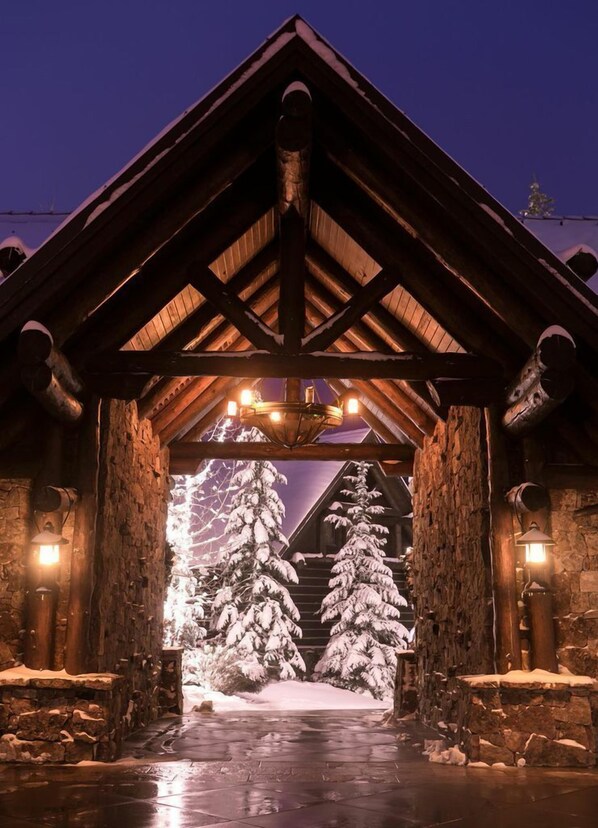 A wooden lodge entrance with a snow-covered landscape and a stone wall.