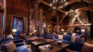A cozy log cabin-style interior with multiple seating areas, a stone fireplace, and a chandelier. - RITZ-CARLTON BACHELOR GULCH RESIDENTIAL SUITE located in the Award winning Hotel (Avon)