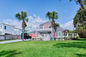 A two-story house with a garage, a covered porch, and a lawn. - Walk to Dining,& the Beach–Chic Cottage, Bikes, Kayak, Golf Cart Available (Santa Rosa Beach)