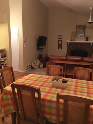 Un coin repas avec une nappe à carreaux, des chaises en osier et un bol rempli de collations.