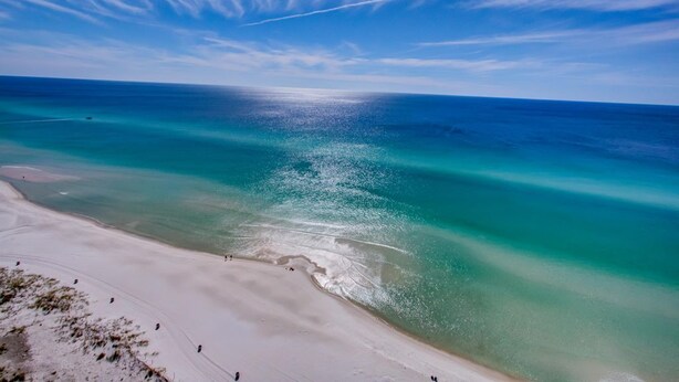 A beach with clear turquoise waters and a sandy shoreline.