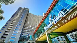 A hotel with a modern facade, a prominent sign, and a high-rise building in the background.