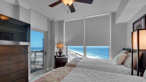A bedroom with two beds, a TV, a dresser, a lamp, and a view of the ocean. -  Gulf Front views- Tower 1-17Th floor-  Pensacola Beach  (Pensacola Beach)