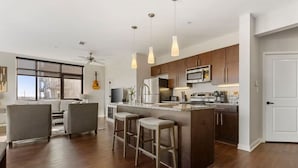 A modern kitchen with dark wood cabinets, stainless steel appliances, and a central island with bar stools.