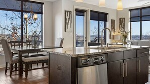 A modern kitchen with a large island, stainless steel appliances, and a view through large windows.