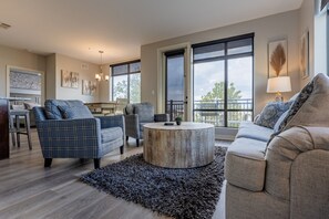 Ein geräumiges Wohnzimmer mit großem Fenster, einem runden Couchtisch und einer Couch.
