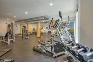 Ein Fitnessstudio mit Laufbändern, Crosstrainern und Kurzhanteln.