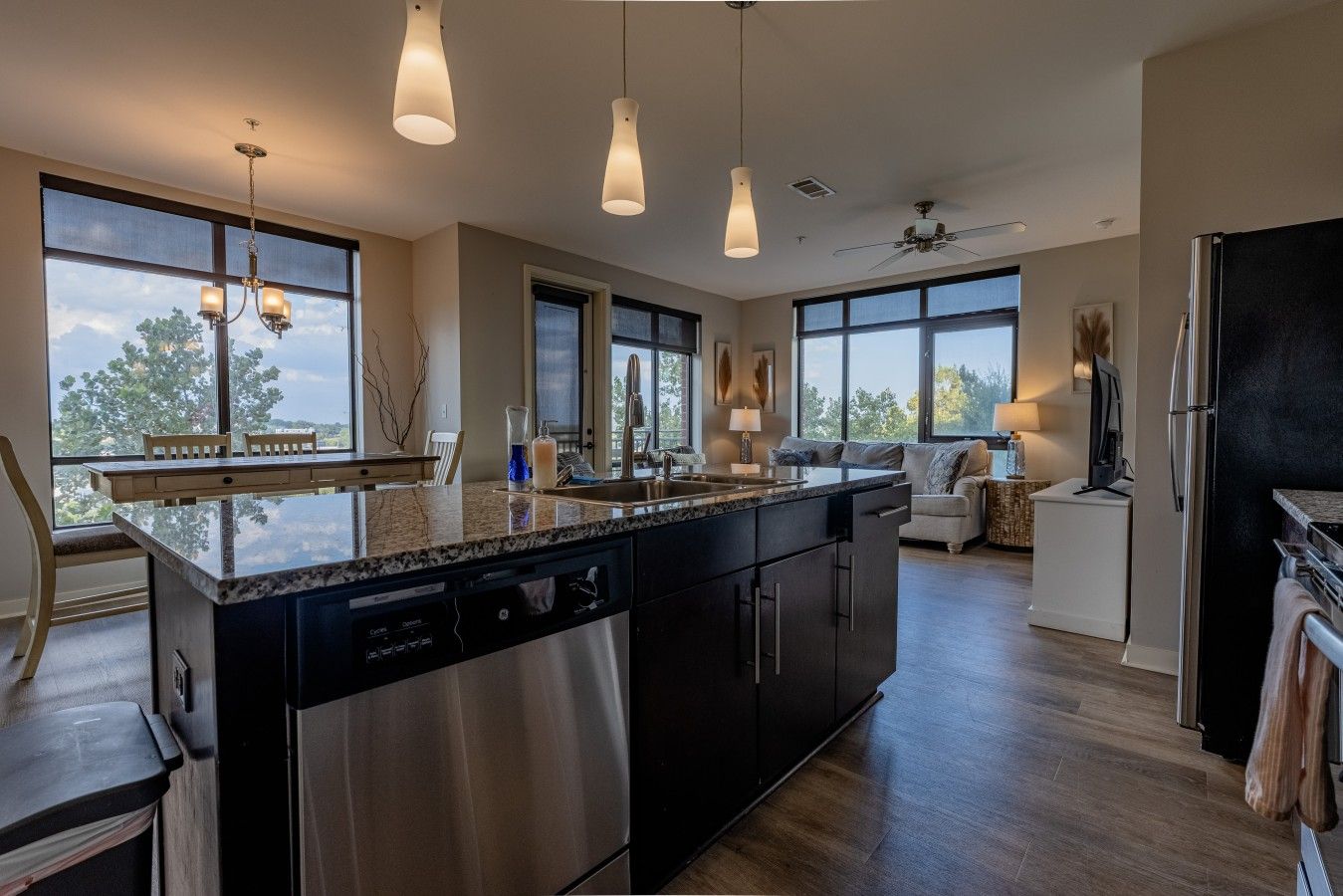 A modern kitchen with a large island, stainless steel appliances, and pendant lighting.