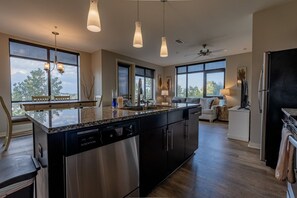 Una cocina moderna con una isla grande, electrodomésticos de acero inoxidable e iluminación colgante.