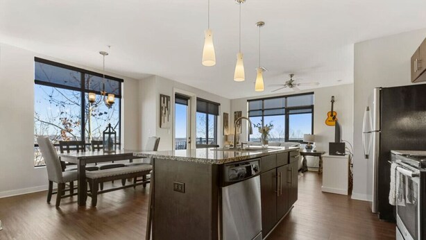 A modern kitchen with a large island, stainless steel appliances, and pendant lighting.