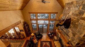 A spacious living room with a stone fireplace, large windows, and a cozy seating area. - Rivamonte by Cottonwood Lodging (Brighton)