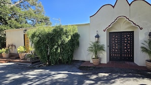 A building with a traditional design, featuring a decorative entrance with a black gate, potted plants, and a clear sky. - Carmel-by-the-Sea Escape (Carmel-By-The-Sea)