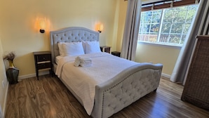 A neatly made bed with a tufted headboard, bedside tables, and wall-mounted lighting. - Carmel-by-the-Sea Escape (Carmel-By-The-Sea)