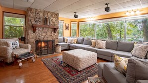 A cozy living room with a stone fireplace, a large sectional sofa, and a wooden bench.