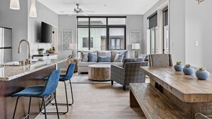 Une cuisine moderne avec un îlot central, des tabourets de bar, un canapé et une table à manger en bois.