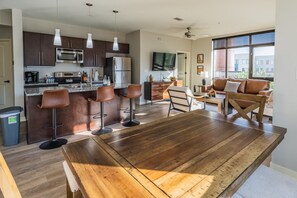 A modern kitchen with dark cabinets, stainless steel appliances, and a bar area with stools.