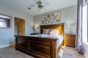 Ein Schlafzimmer mit einem hölzernen Bett, zwei Nachttischlampen, einem Deckenventilator und Kunstwerken an der Wand.