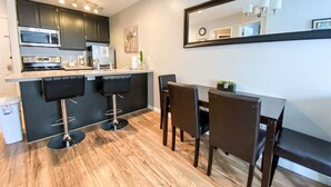 A modern kitchen with dark cabinets, a stainless steel oven, and a bar area with stools. - Inn Building Condo #206 Beautiful updated condo (Garden City)