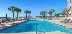 A swimming pool with lounge chairs and palm trees.