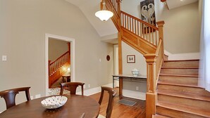 A dining area with a wooden table and chairs, a staircase with wooden railings, and a light fixture above the table. - 2-3 N stays - Spacious and Comfy, Walk to Whole Foods, bars and shops, sleeps 12 (New Orleans)