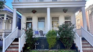 A two-story house with a balcony, a front porch, and a staircase leading to the entrance. - 2-3 N stays - Spacious and Comfy, Walk to Whole Foods, bars and shops, sleeps 12 (New Orleans)