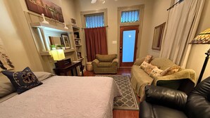 A hotel room with a bed, a leather sofa, a small armchair, a desk with a lamp, and a window with curtains. - 2-3 N stays - Spacious and Comfy, Walk to Whole Foods, bars and shops, sleeps 12 (New Orleans)